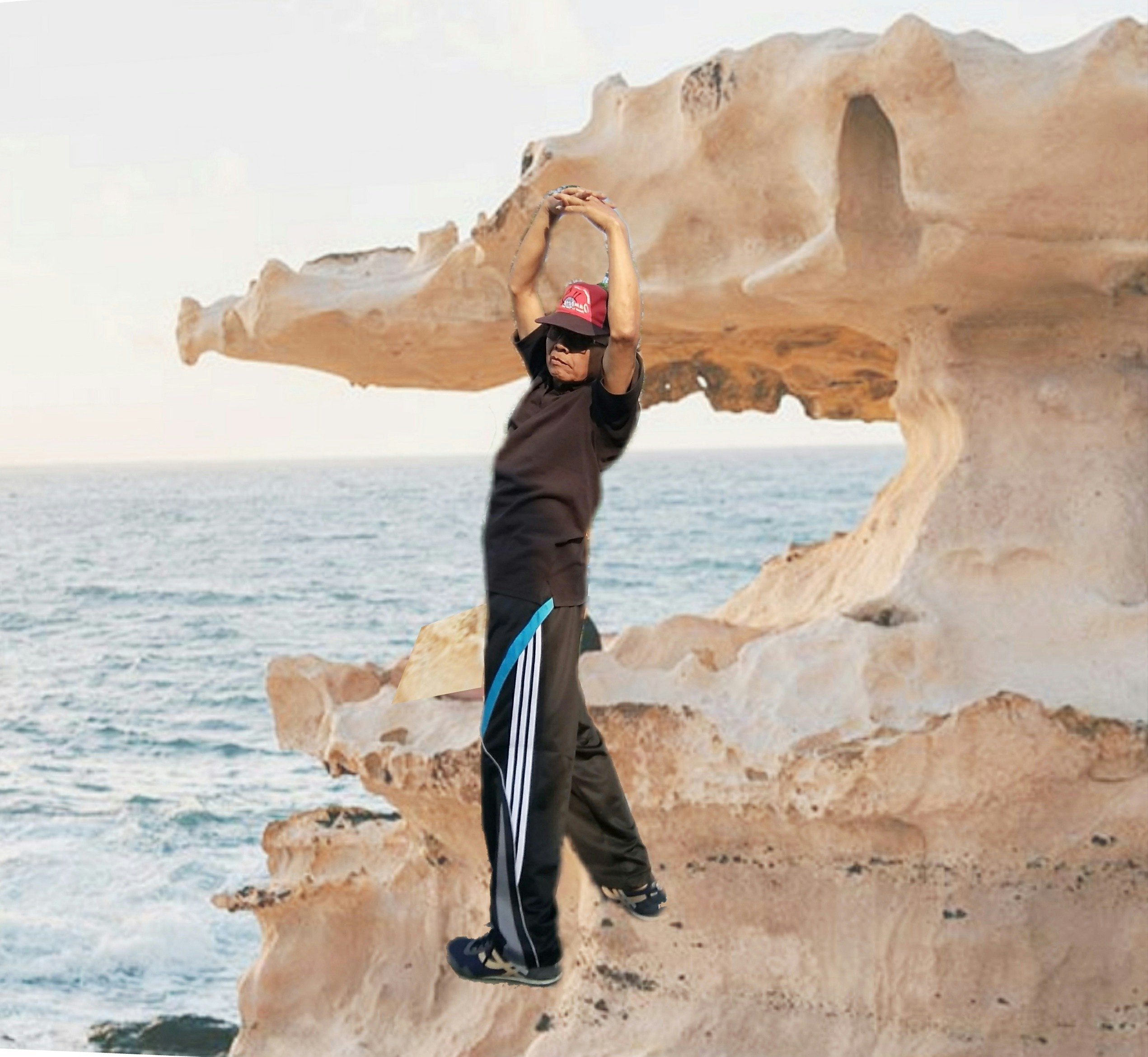 a young boy standing on top of a cliff next to the ocean