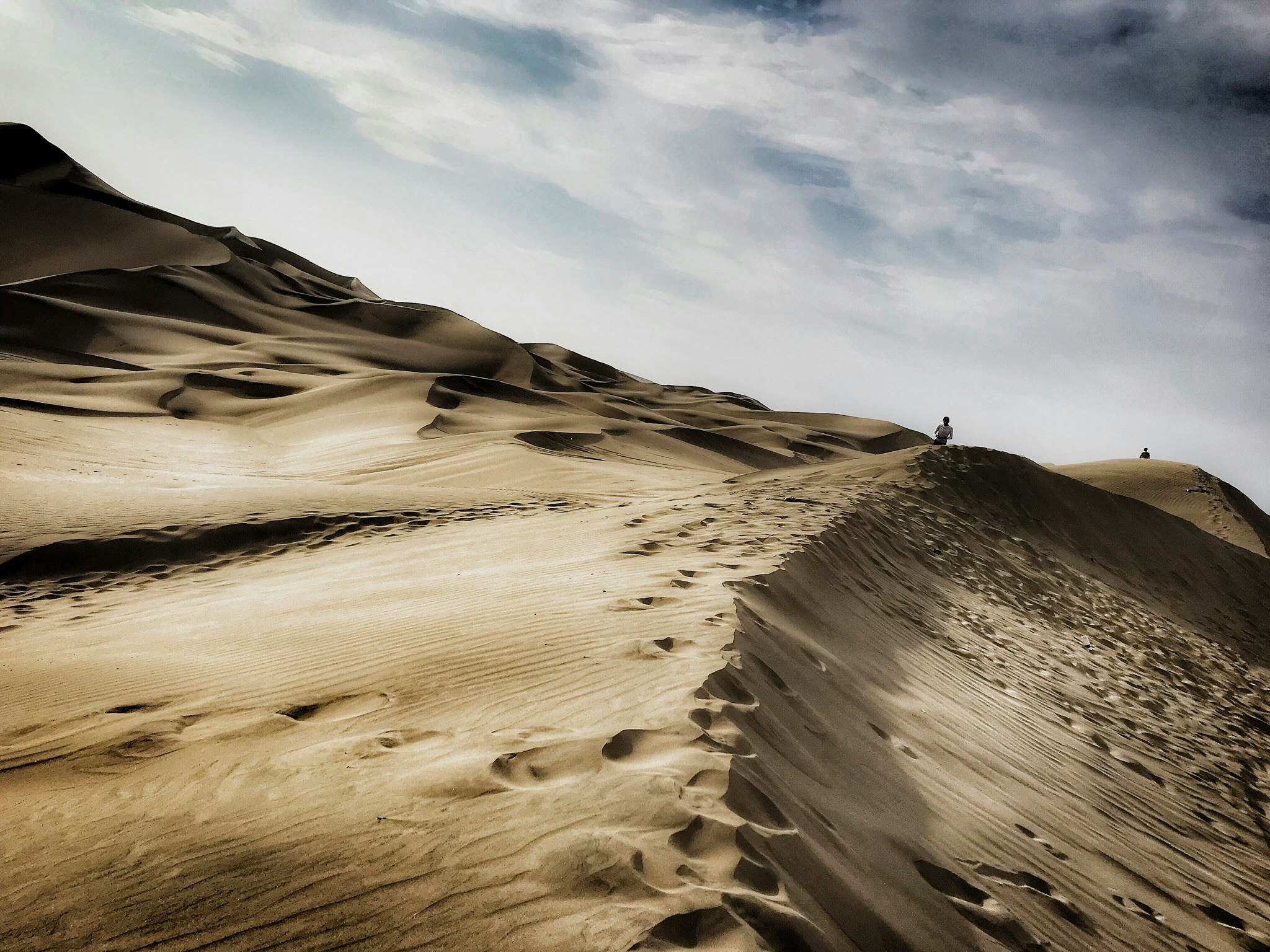 person standing on hill under white cloud blue skies